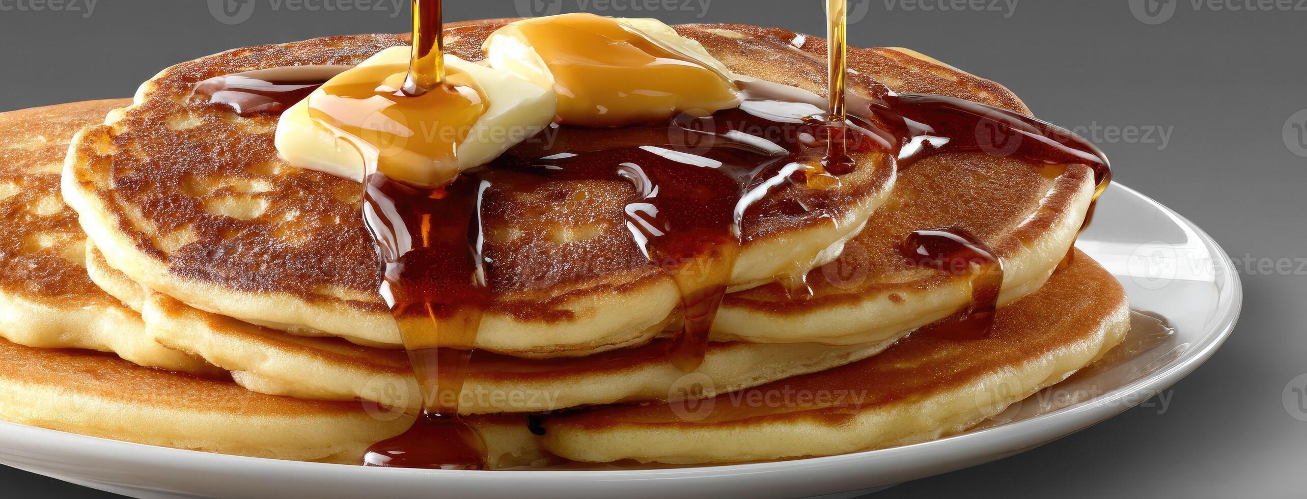 A plate of pancakes with syrup being poured over them photo
