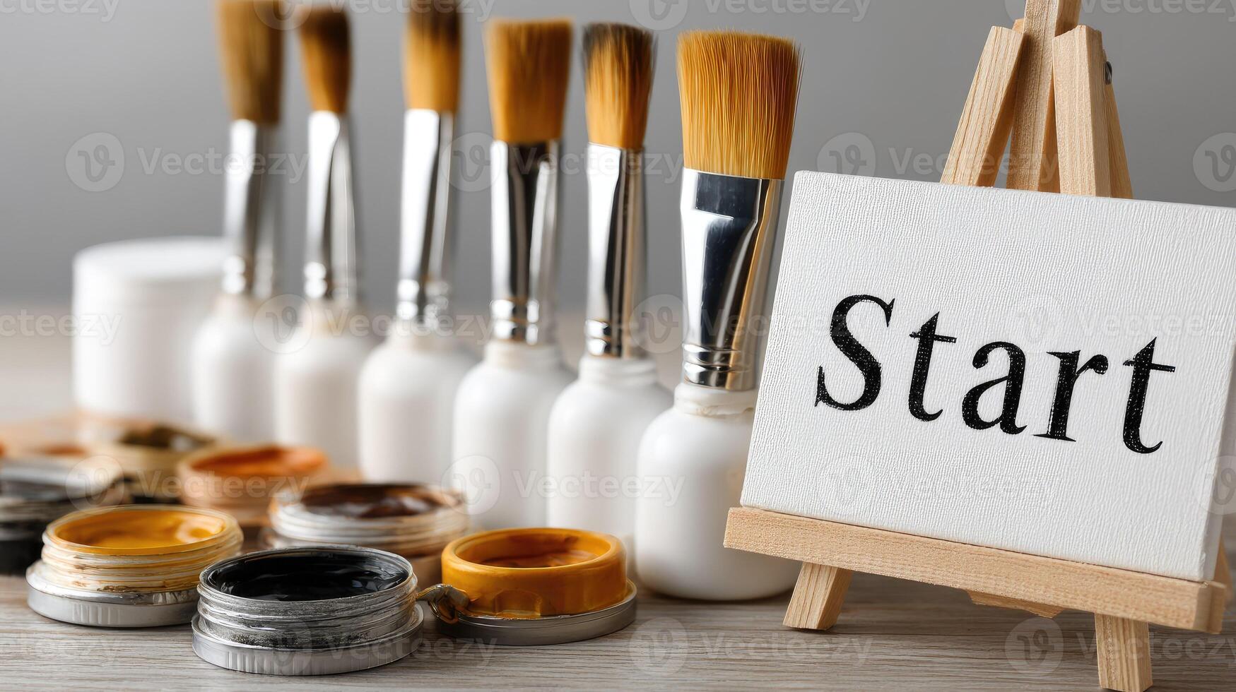 Paint brushes and paint on easel with start sign photo
