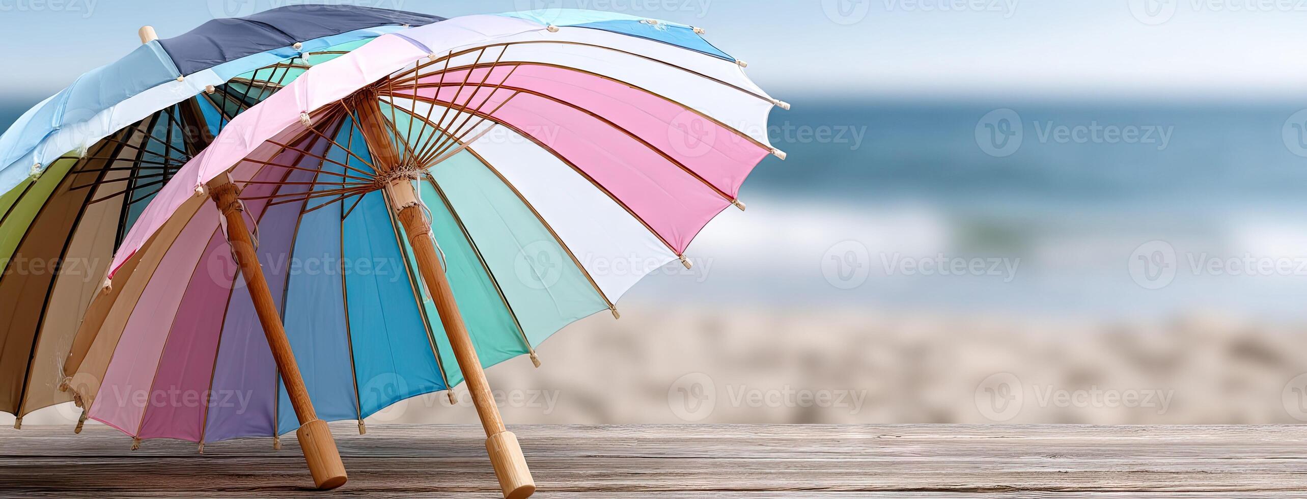 Two colorful umbrellas on a wooden table near the ocean photo