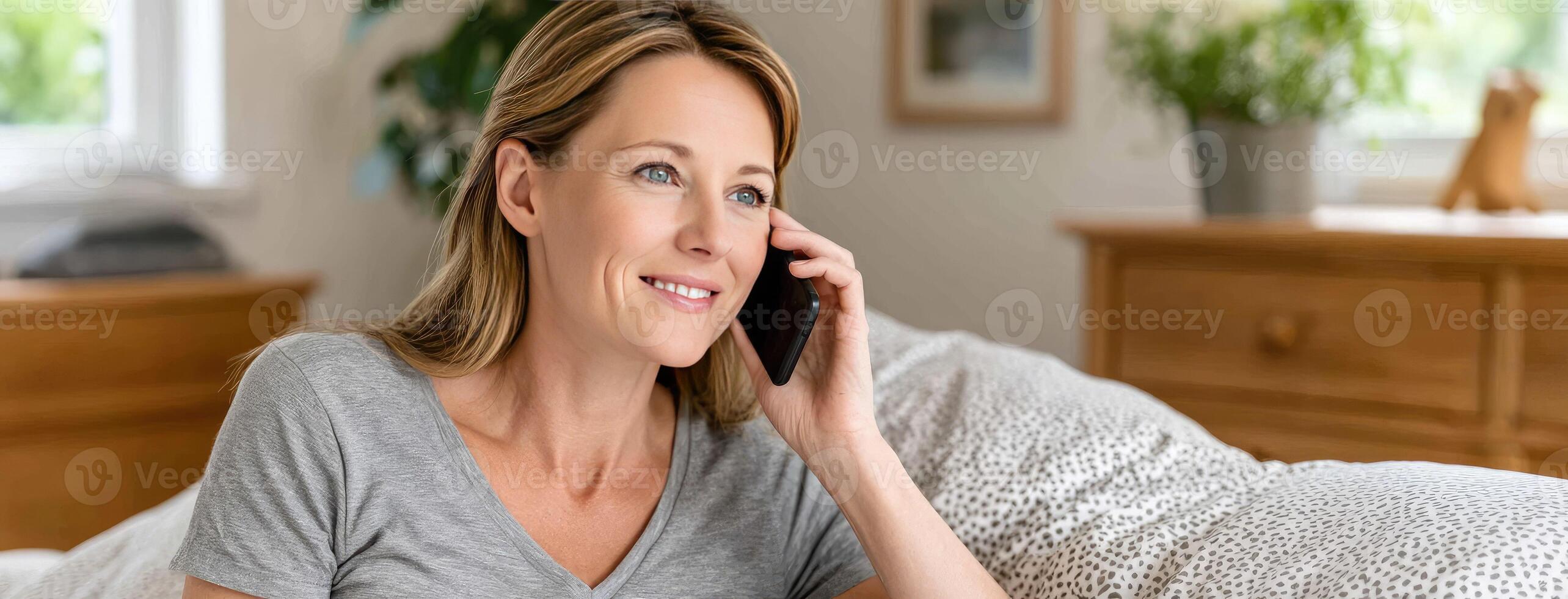 A woman is talking on the phone while laying on a couch photo