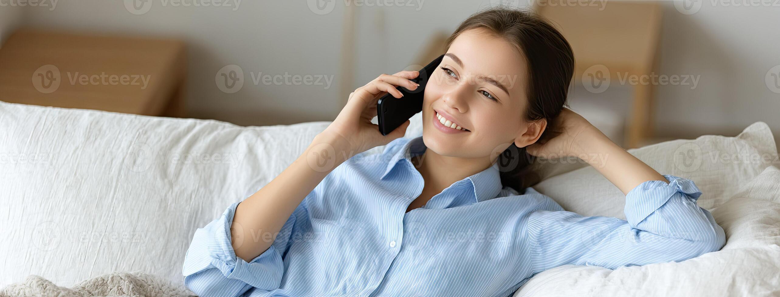 A woman is laying on a couch and talking on a cell phone photo