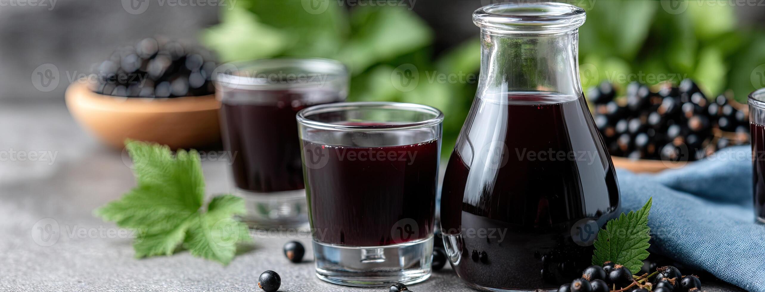 Black currant juice in a glass bottle and a glass of black currant juice photo