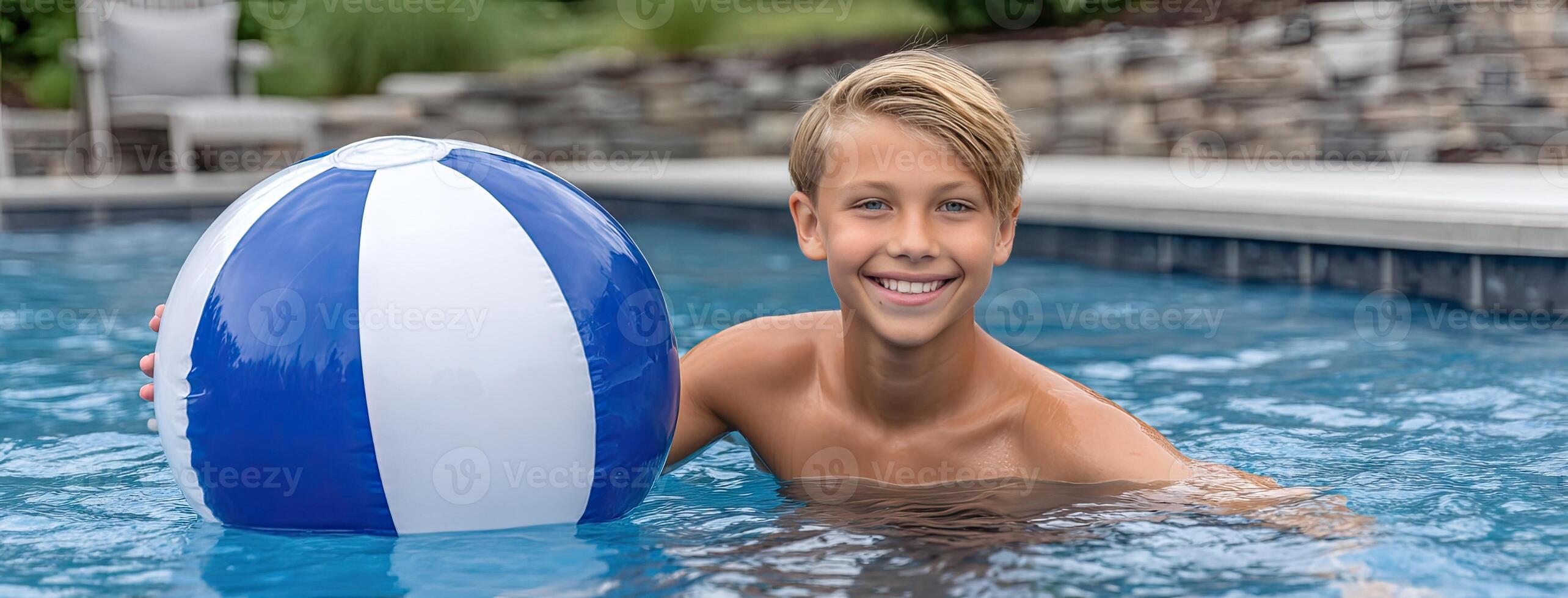 A boy is smiling while holding a blue and white beach ball photo