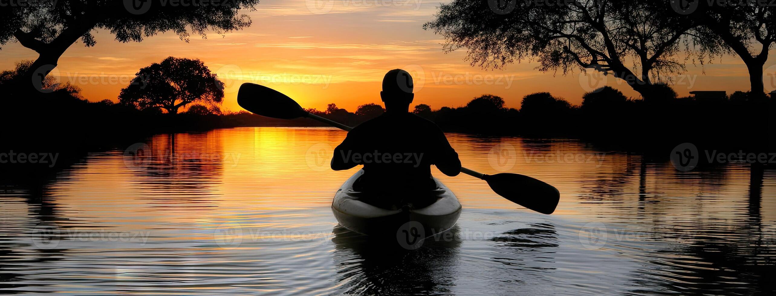A person in a canoe paddling at sunset photo