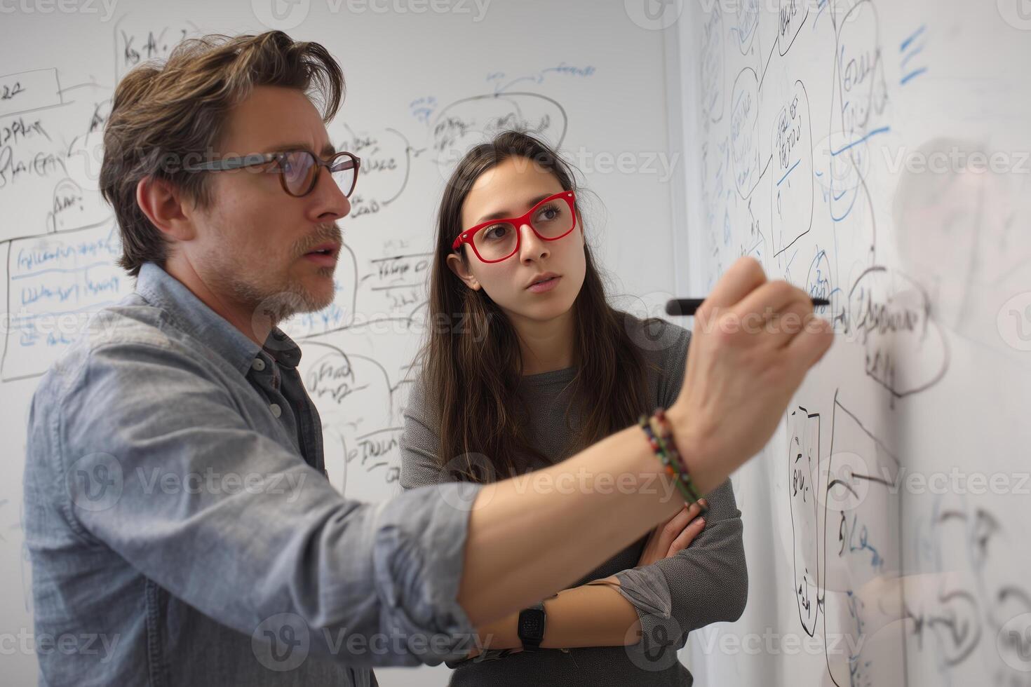 Collaboration between two professionals as they brainstorm ideas on a whiteboard in a modern office setting photo