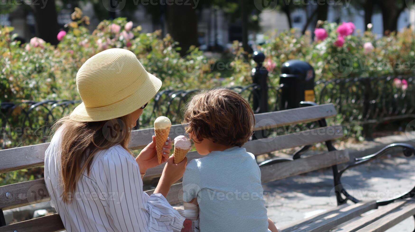 Mother and child enjoying ice cream on a sunny day in a city park surrounded by blooming flowers photo