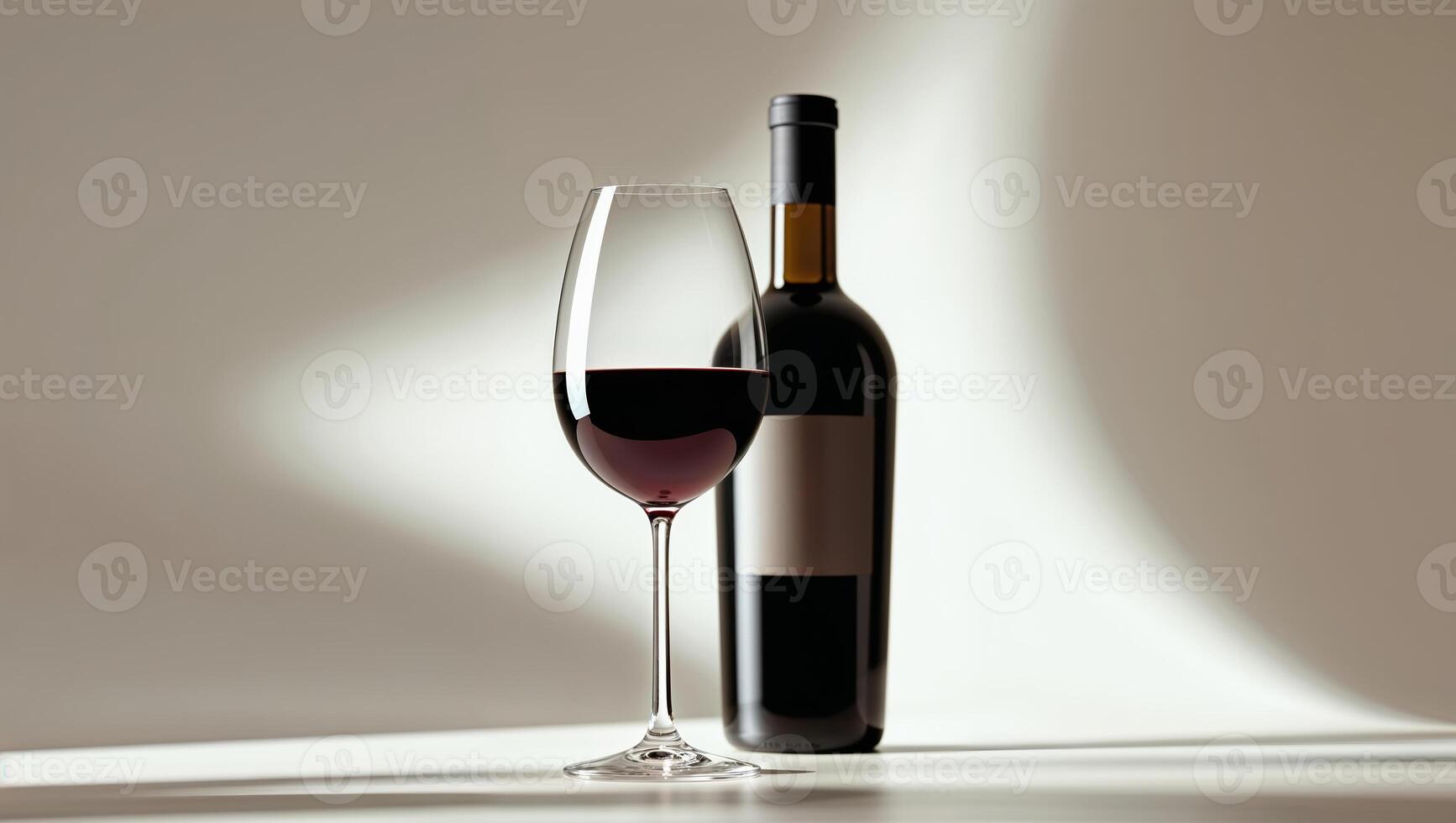 Elegant red wine glass alongside a dark bottle in a minimalistic setting with soft shadows photo