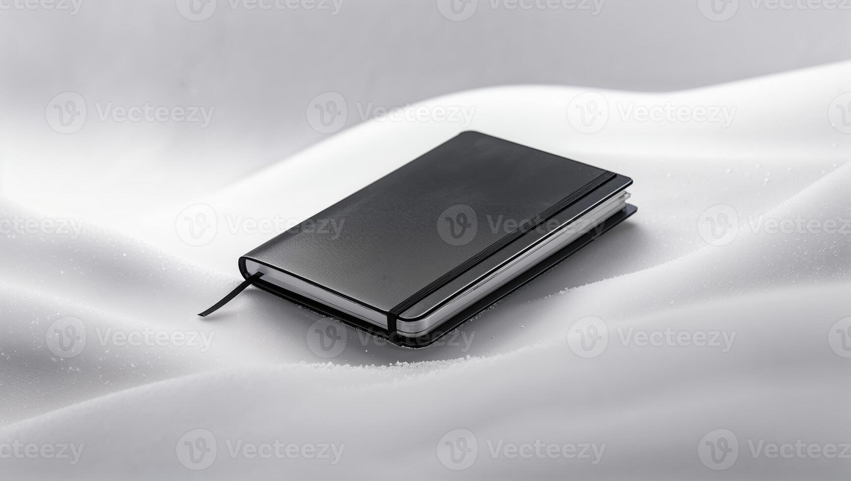 Stylish black notebook resting on soft white snow creating a serene winter atmosphere photo