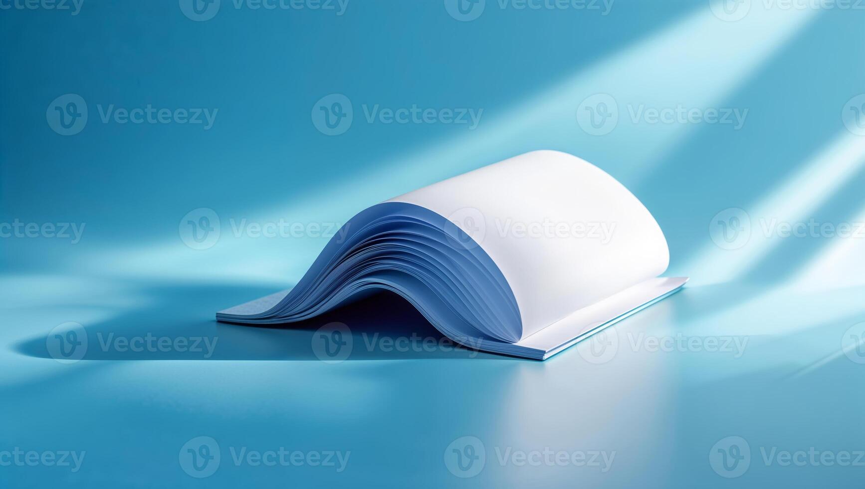 Open book with blue pages resting on a blue surface illuminated by soft light in a minimalist setting photo