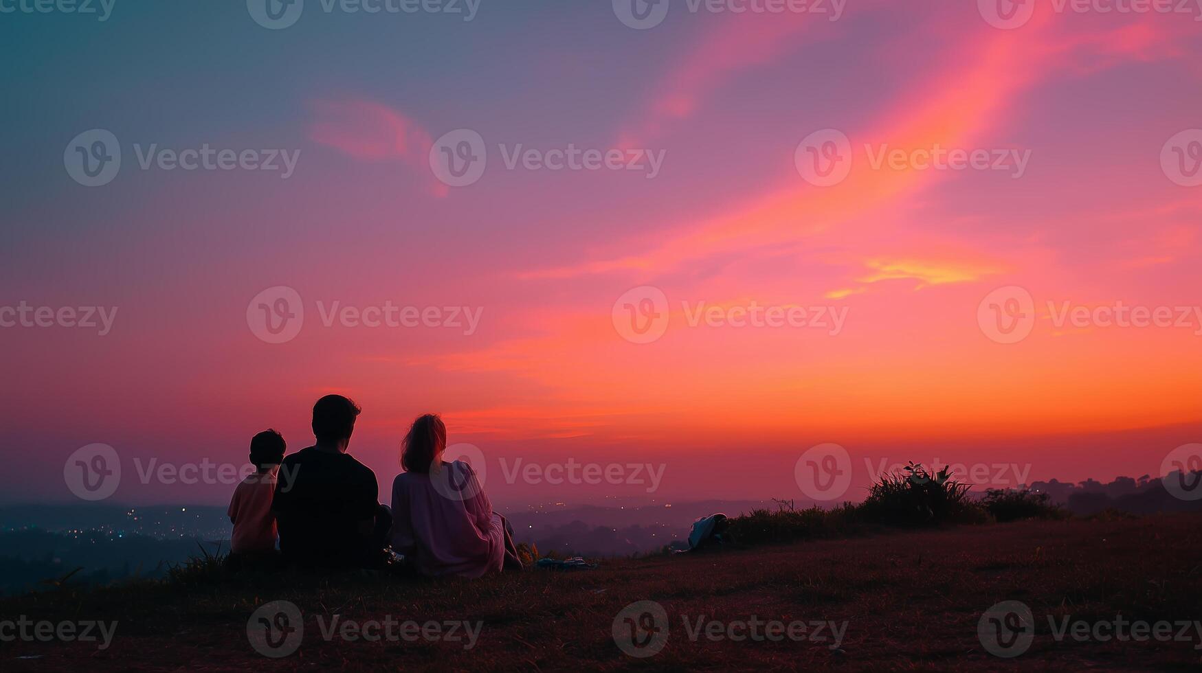 Friends enjoy a colorful sunset view from a hilltop overlooking a valley on a serene evening photo