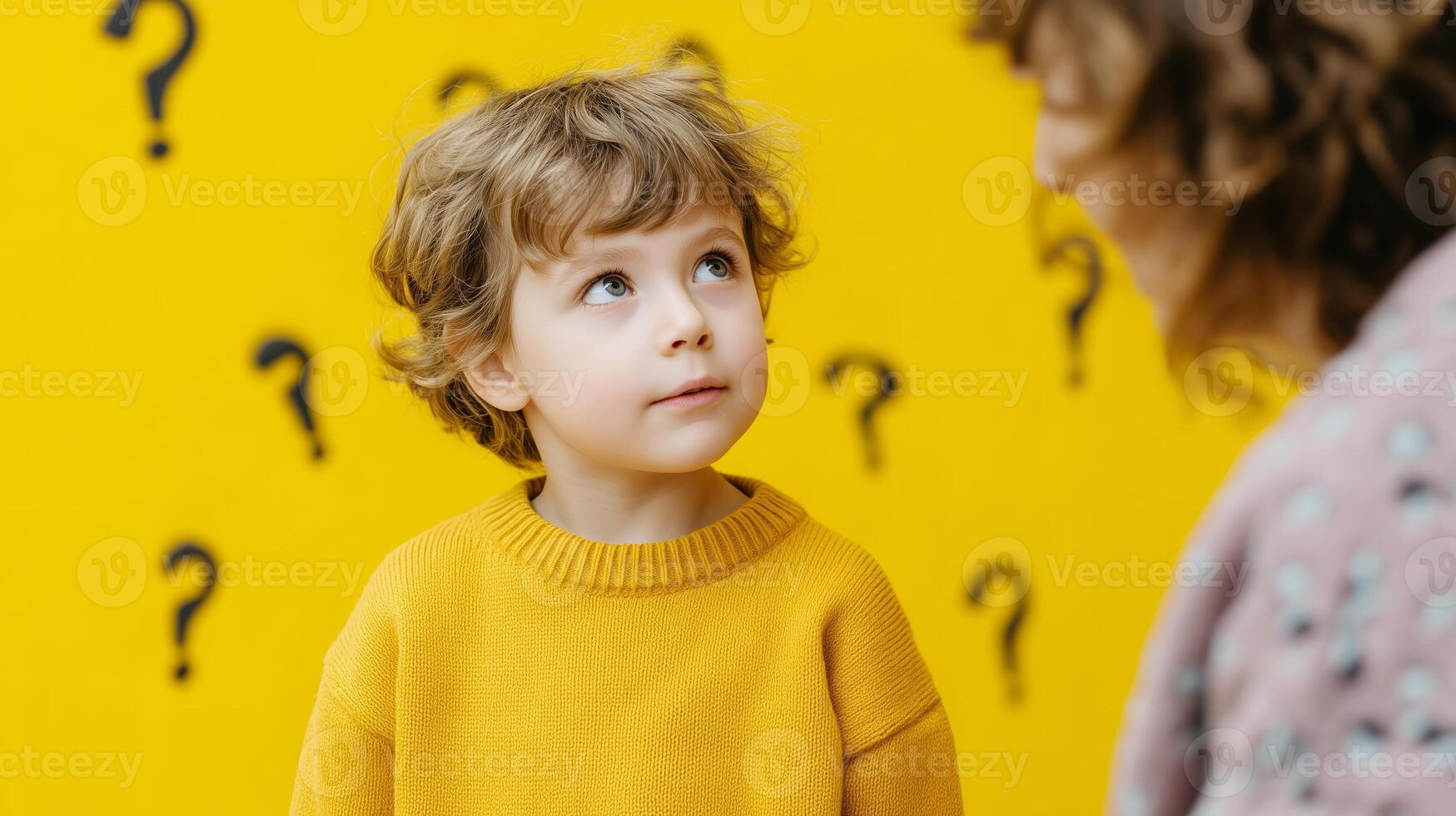 Curious child engages in conversation with an adult in a bright yellow room filled with question marks photo