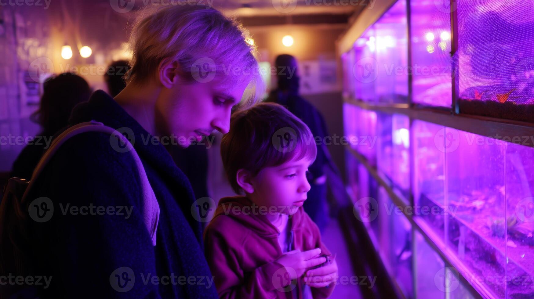 Mother and child explore illuminated aquarium at night in a cozy setting photo