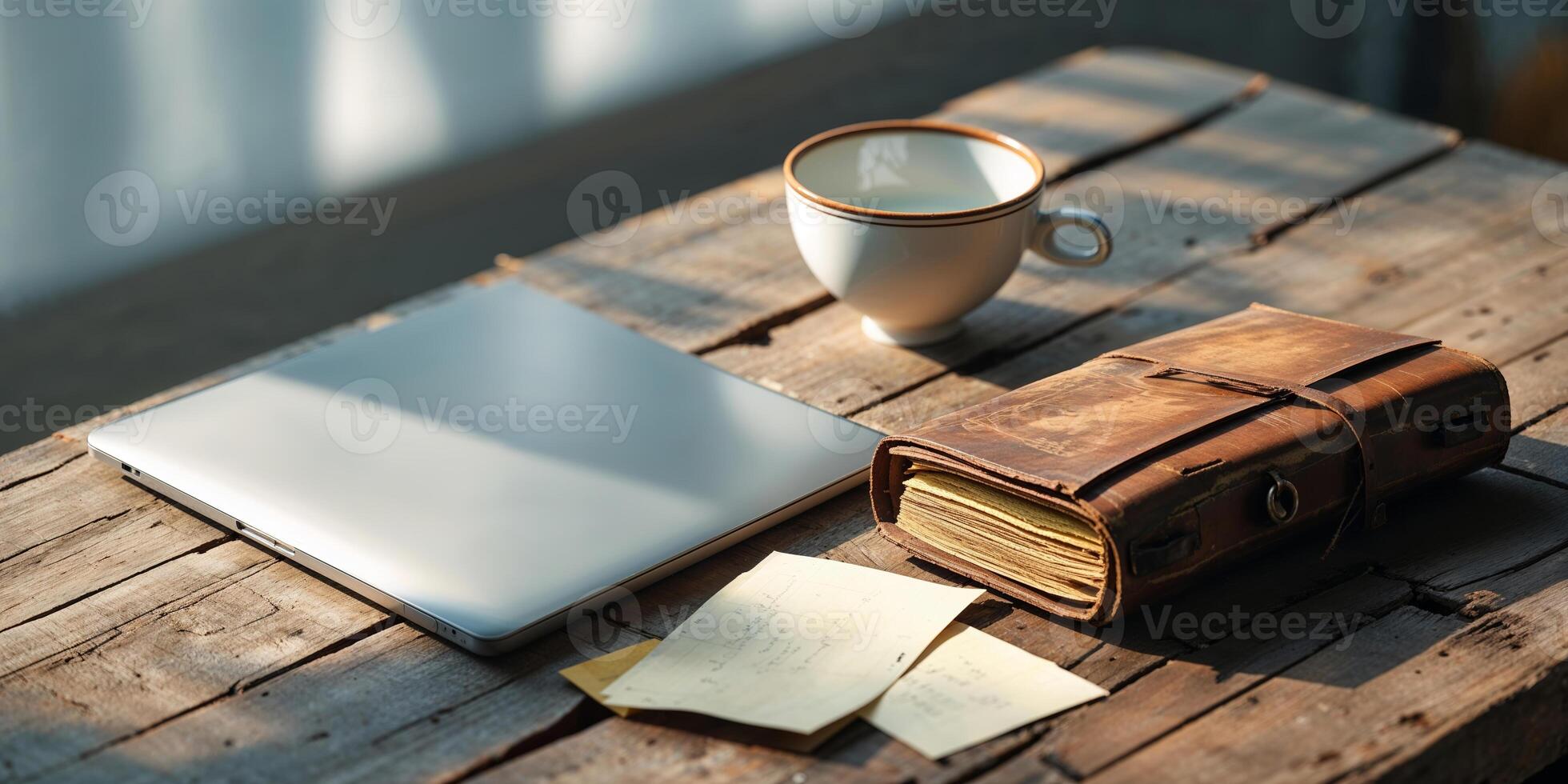 Workspace setup with laptop, notebook, and coffee in warm sunlight during a quiet morning photo