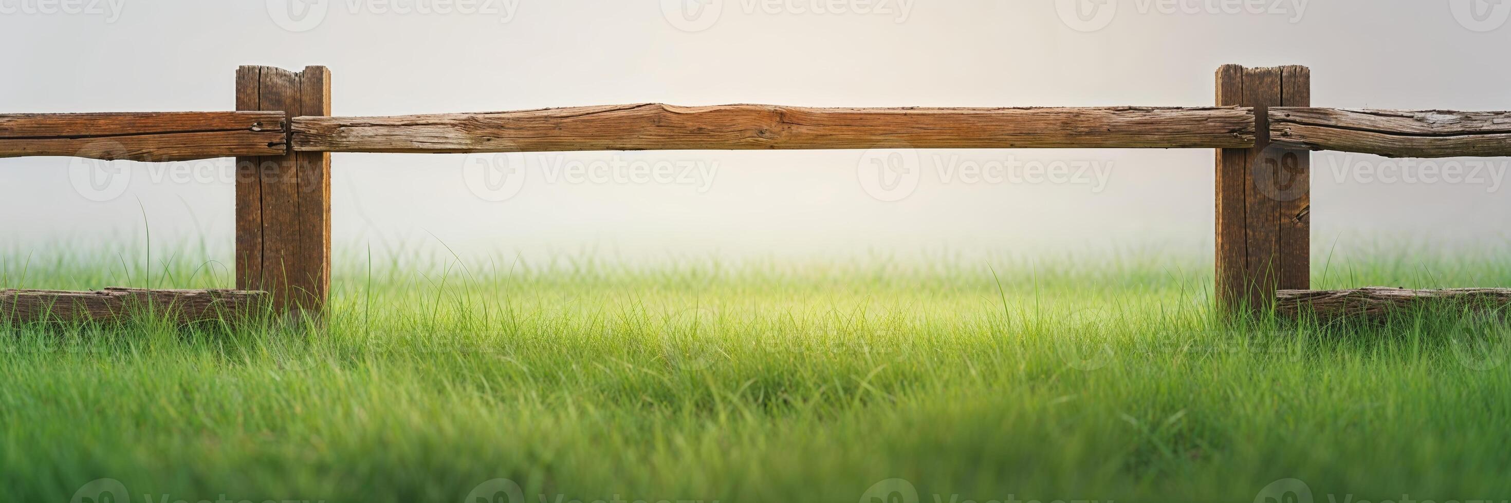 Morning fog blankets a grassy field beside a rustic wooden fence in a serene atmosphere photo