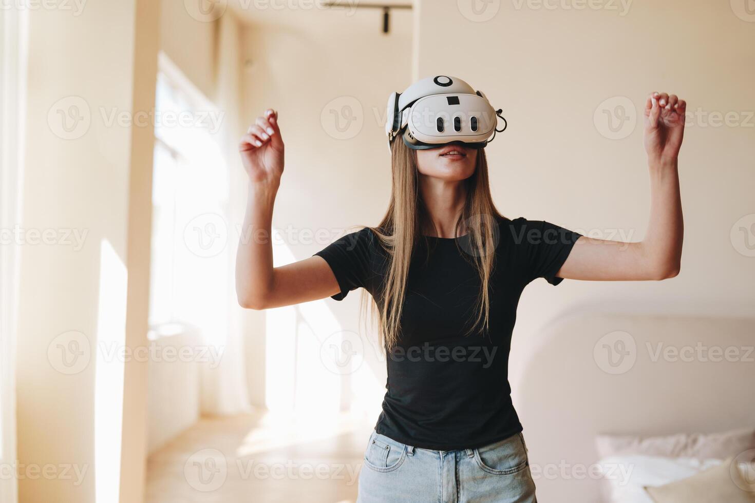 Woman experiencing virtual reality in a bright room during daylight hours while engaging in an interactive digital environment photo