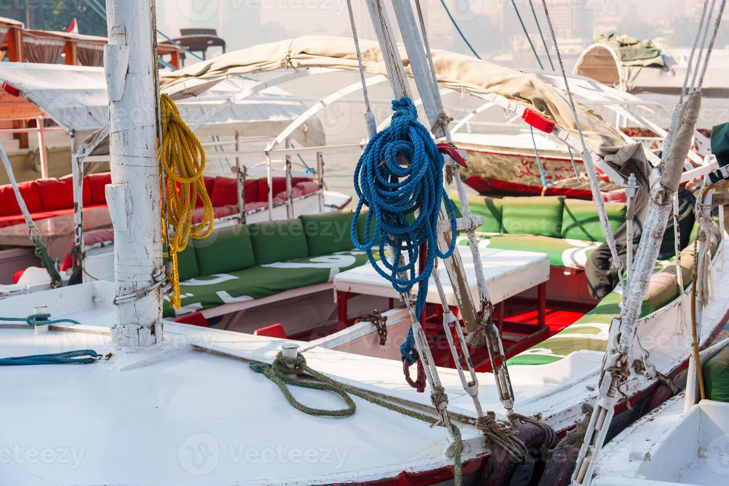 Colorful ropes and cushions adorn traditional boats at a bustling riverside dock in the warm afternoon light photo