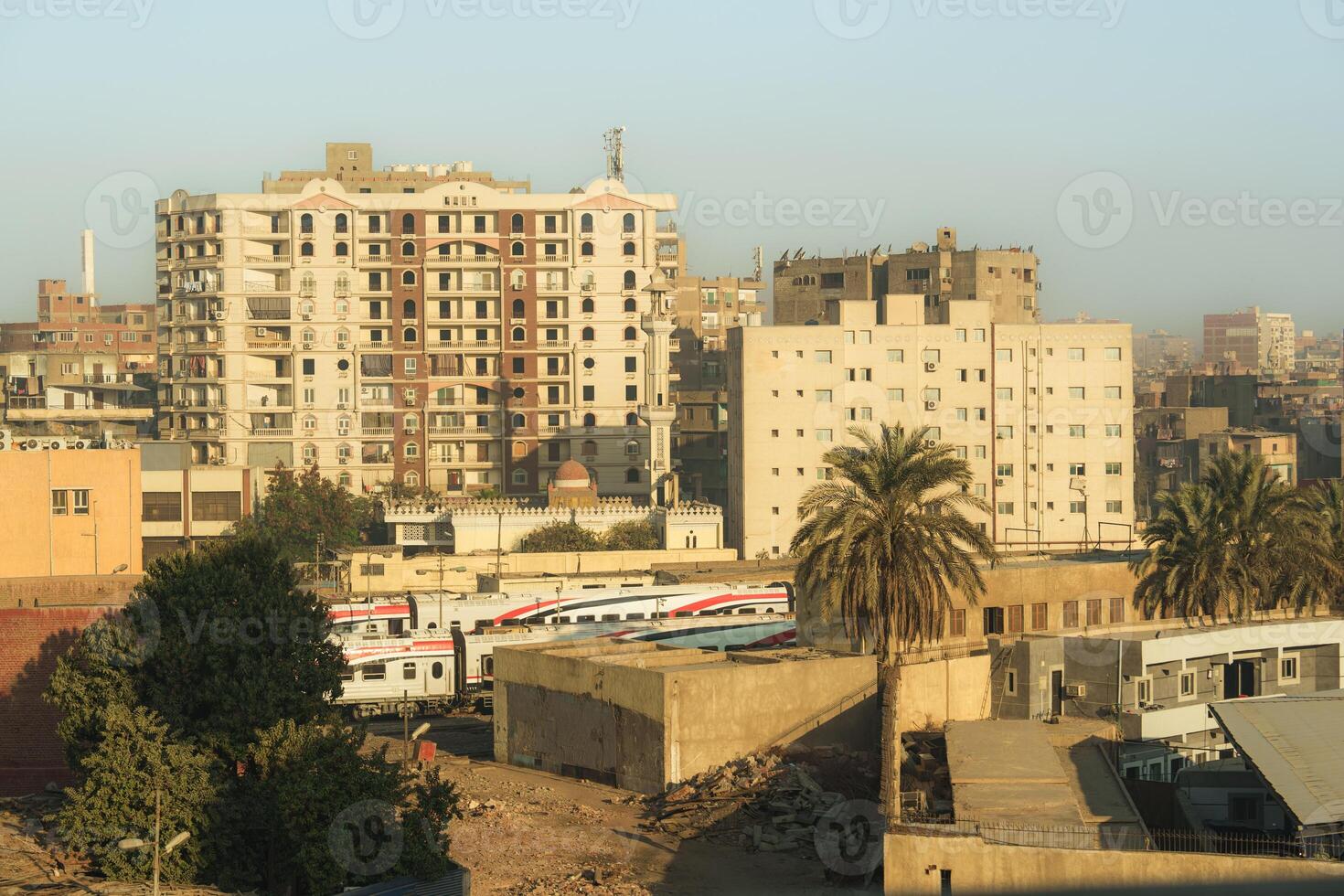 Urban landscape in Egypt showcasing modern buildings and palm trees during golden hour photo
