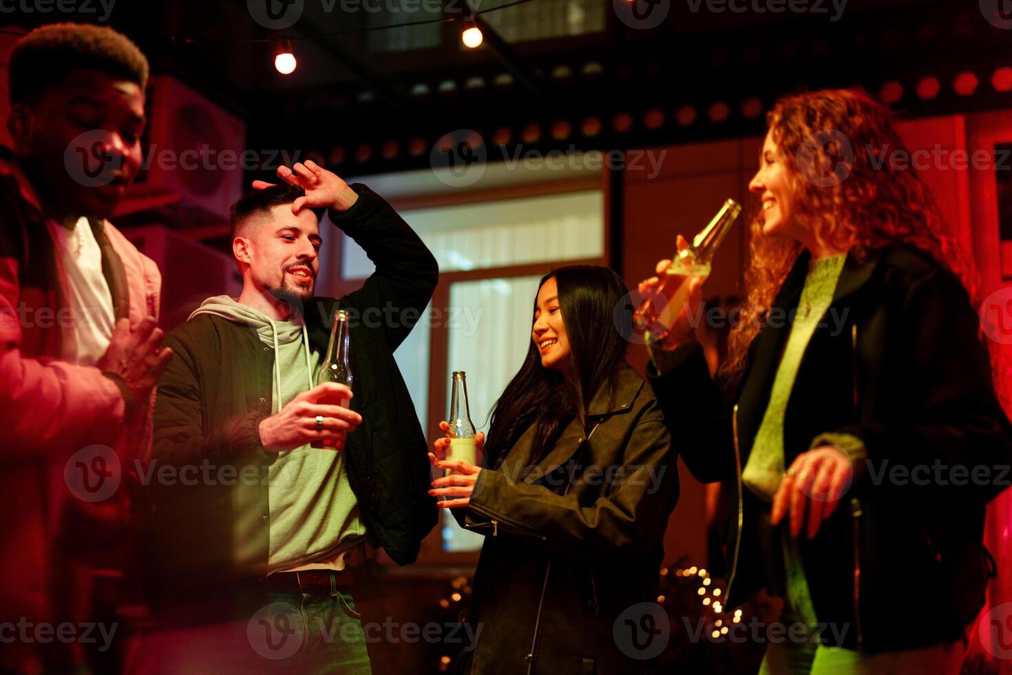 Friends enjoying drinks and dancing together at a lively indoor gathering during the evening photo