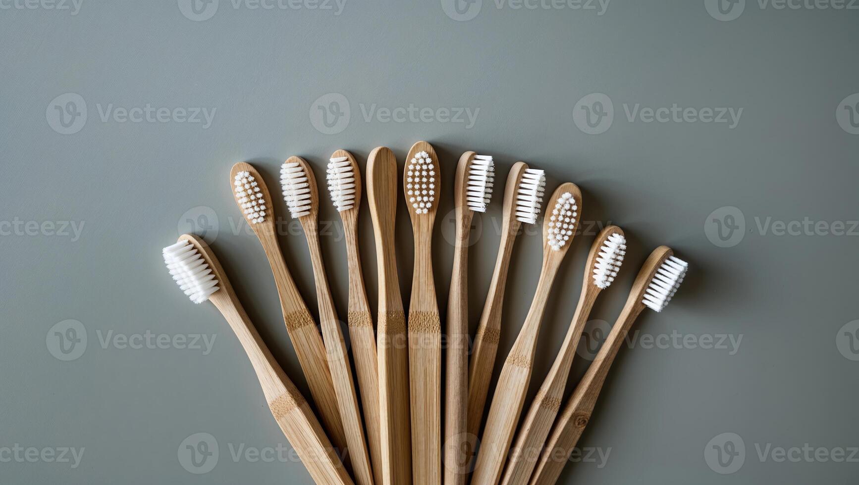 Collection of eco-friendly bamboo toothbrushes arranged in a neat pattern on a gray surface photo