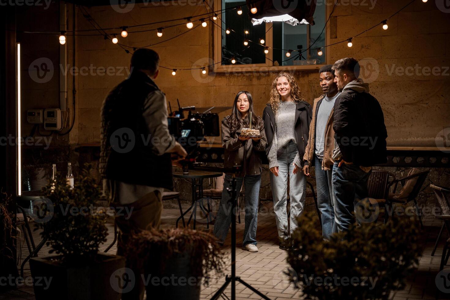 Outdoor group photoshoot during evening light at a cozy location with string lights in the background photo