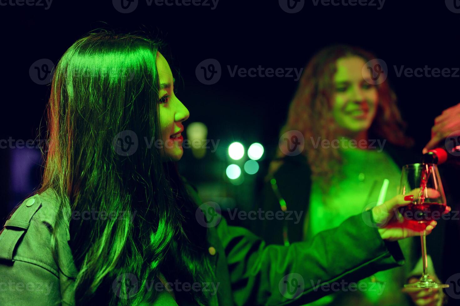 Friends enjoying drinks at a vibrant night gathering with green lighting in a festive atmosphere photo