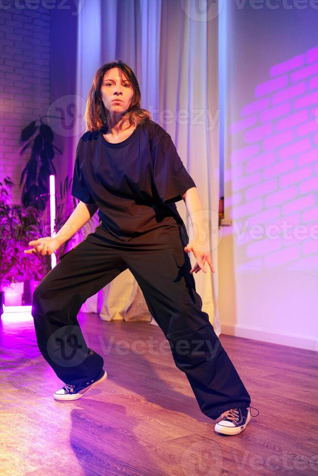 Performer showcases dynamic dance moves in a vibrant indoor studio setting with colorful lighting photo