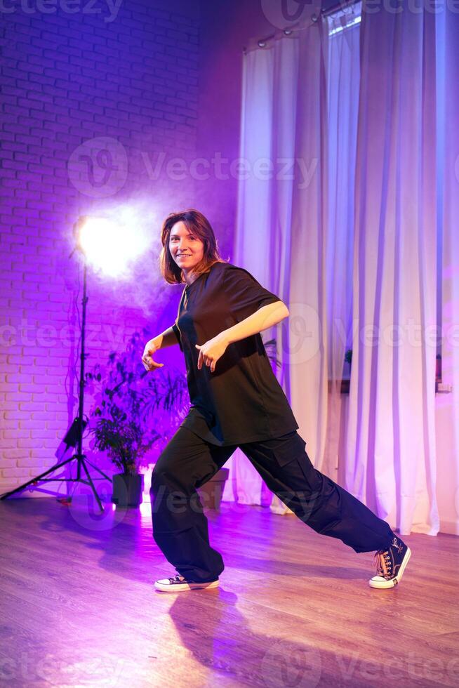 Dancer performs dynamic routine in studio with colorful lighting and soft curtains during evening session photo