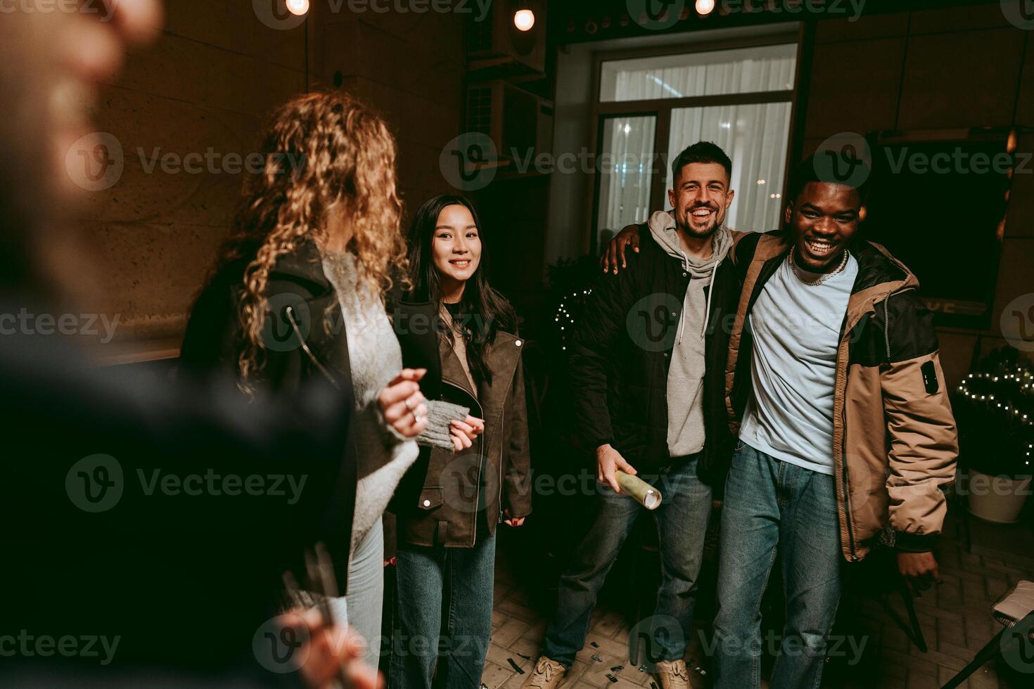 Group of friends enjoying a joyful evening gathering indoors at a cozy location with soft lighting and laughter photo