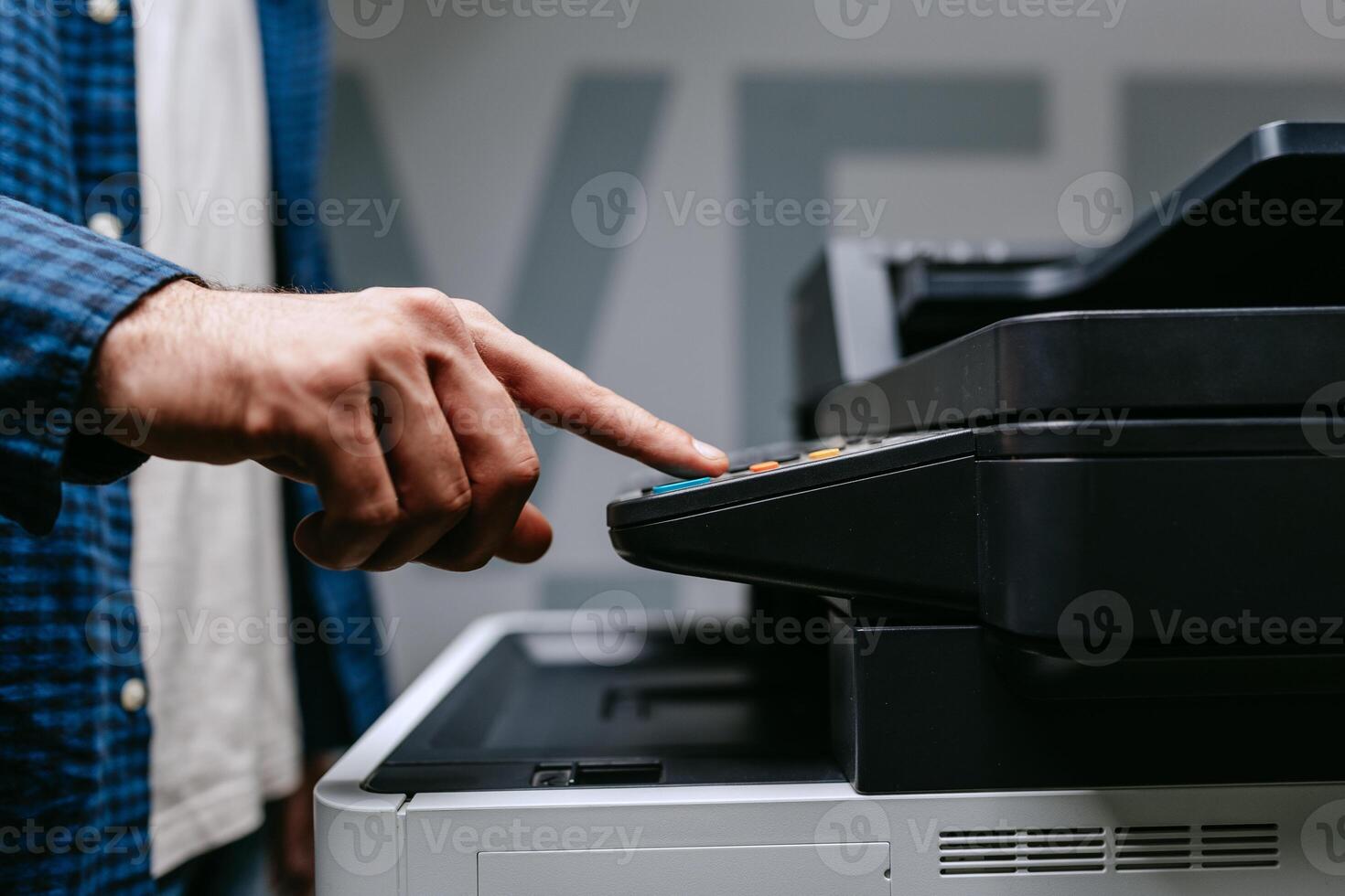 Person operating a copier in an office setting during daylight hours while preparing to make copies of documents photo