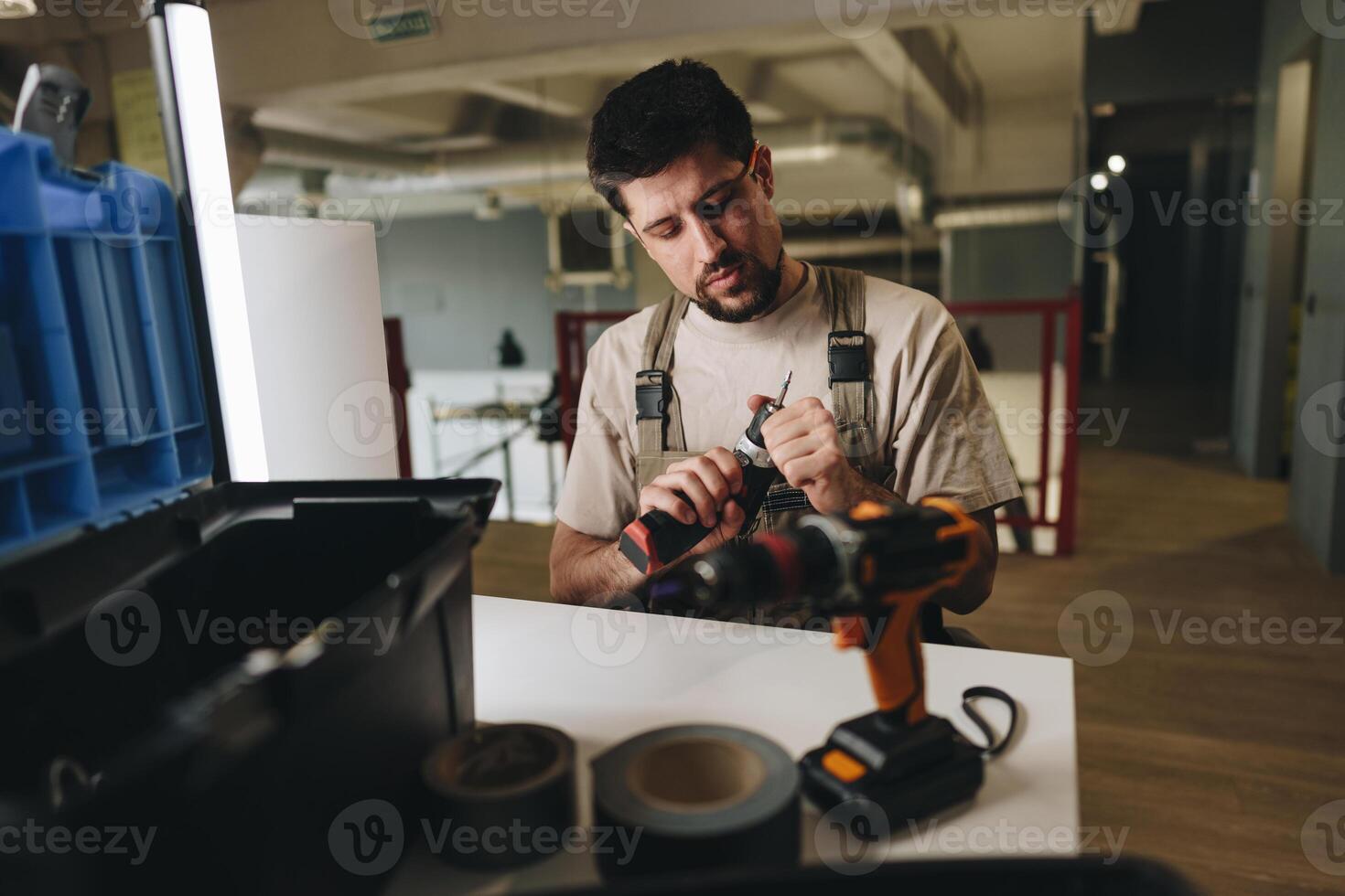 Craftsman prepares tools at a workbench in a modern workshop space during the day photo
