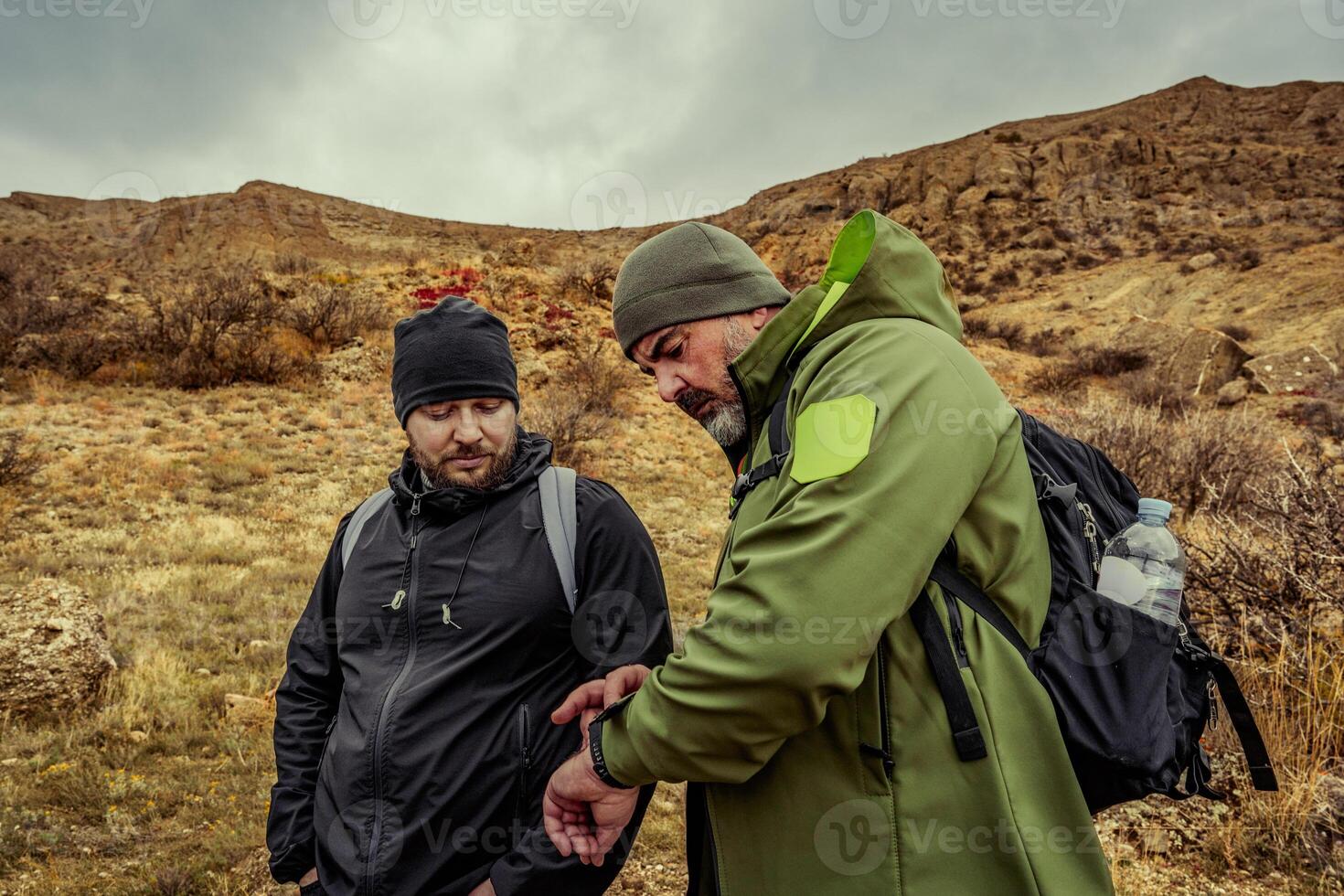 Two hikers discussing navigation on a cloudy day in a mountainous landscape during an outdoor adventure in nature photo