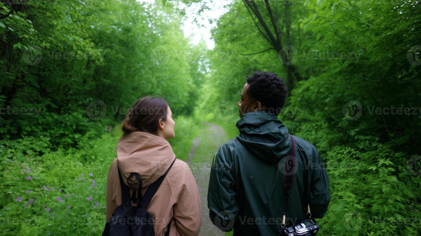 Couple walking on a lush green trail surrounded by vibrant foliage during a sunny afternoon in a peaceful forest photo