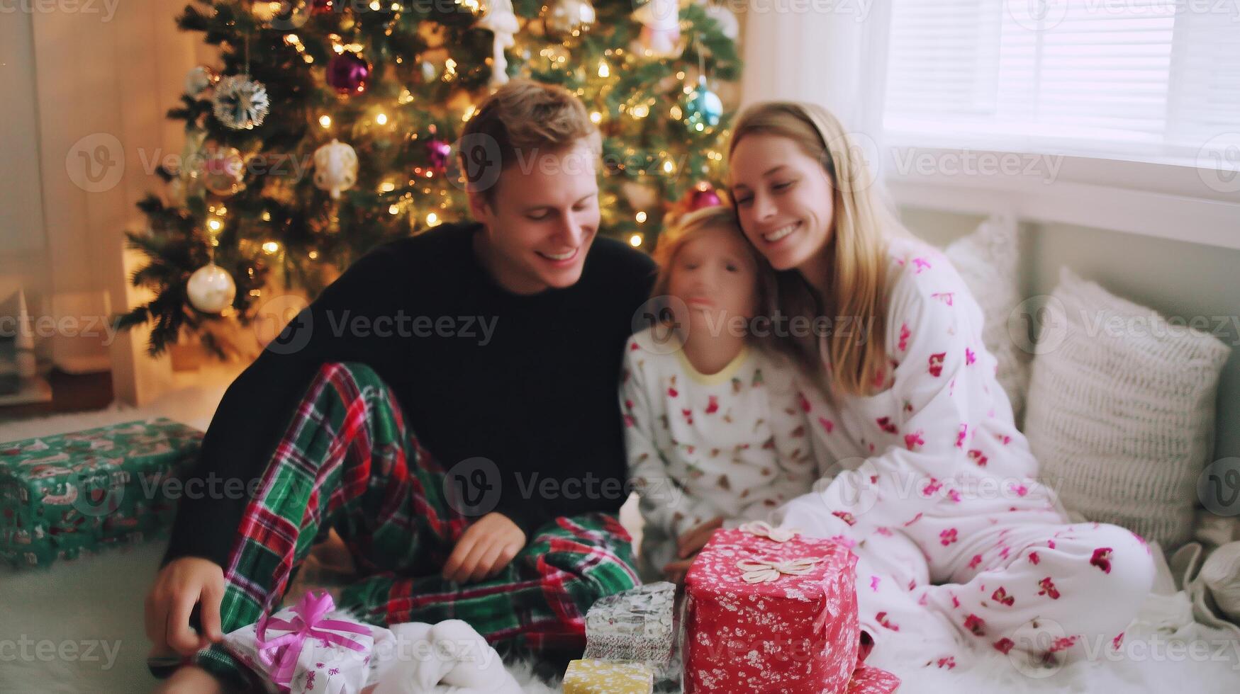 Family enjoys a cozy Christmas morning by the tree while unwrapping gifts in festive pajamas photo