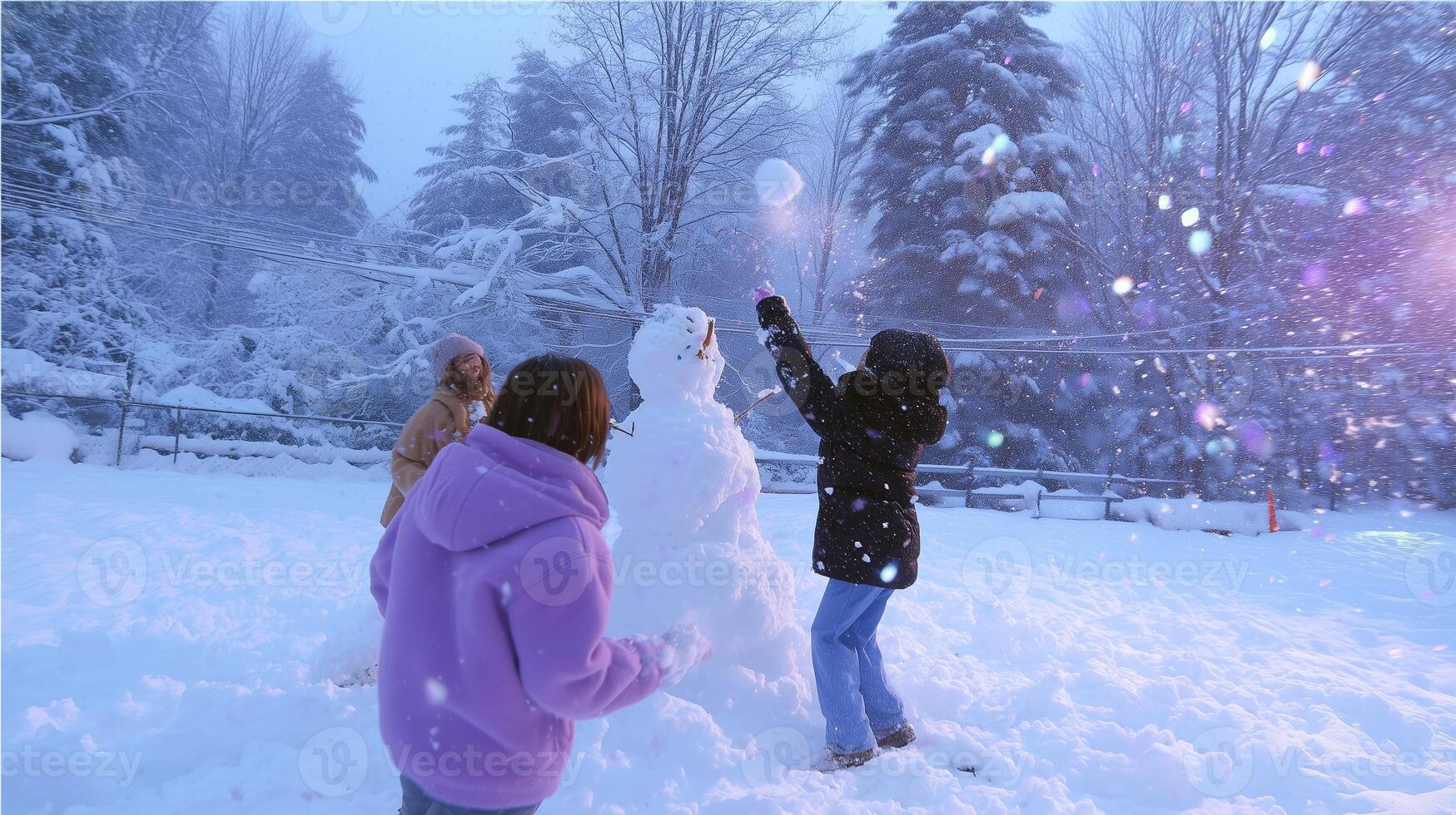 Children joyfully build a snowman in a snowy landscape during winter at a suburban park in the early evening photo