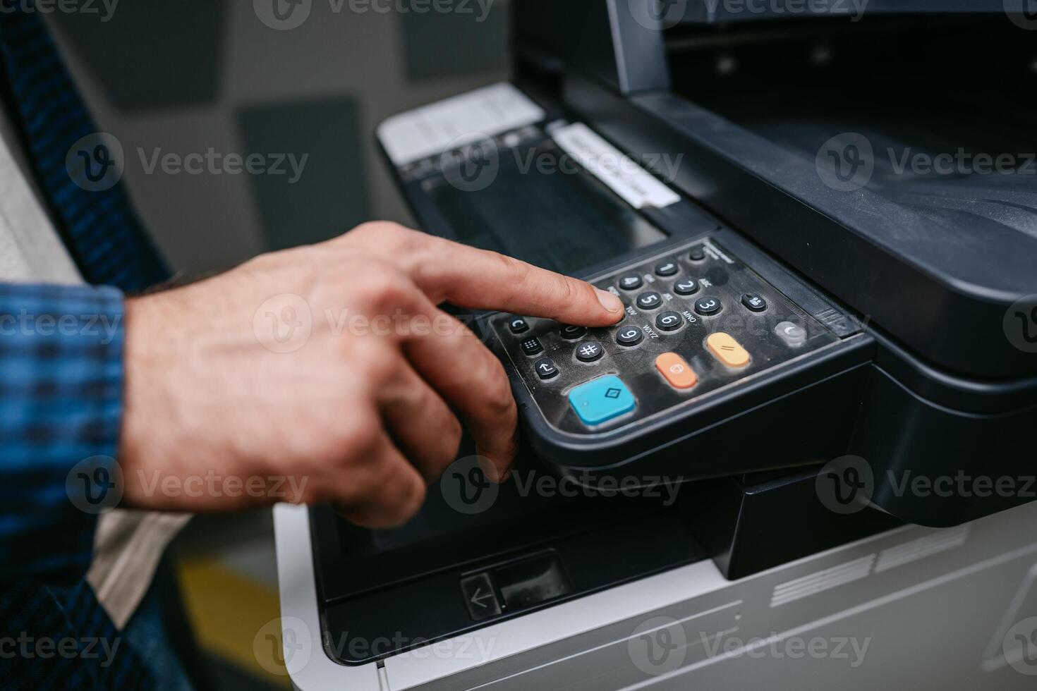 Man using a multifunction printer to operate the control panel in an office environment during working hours photo