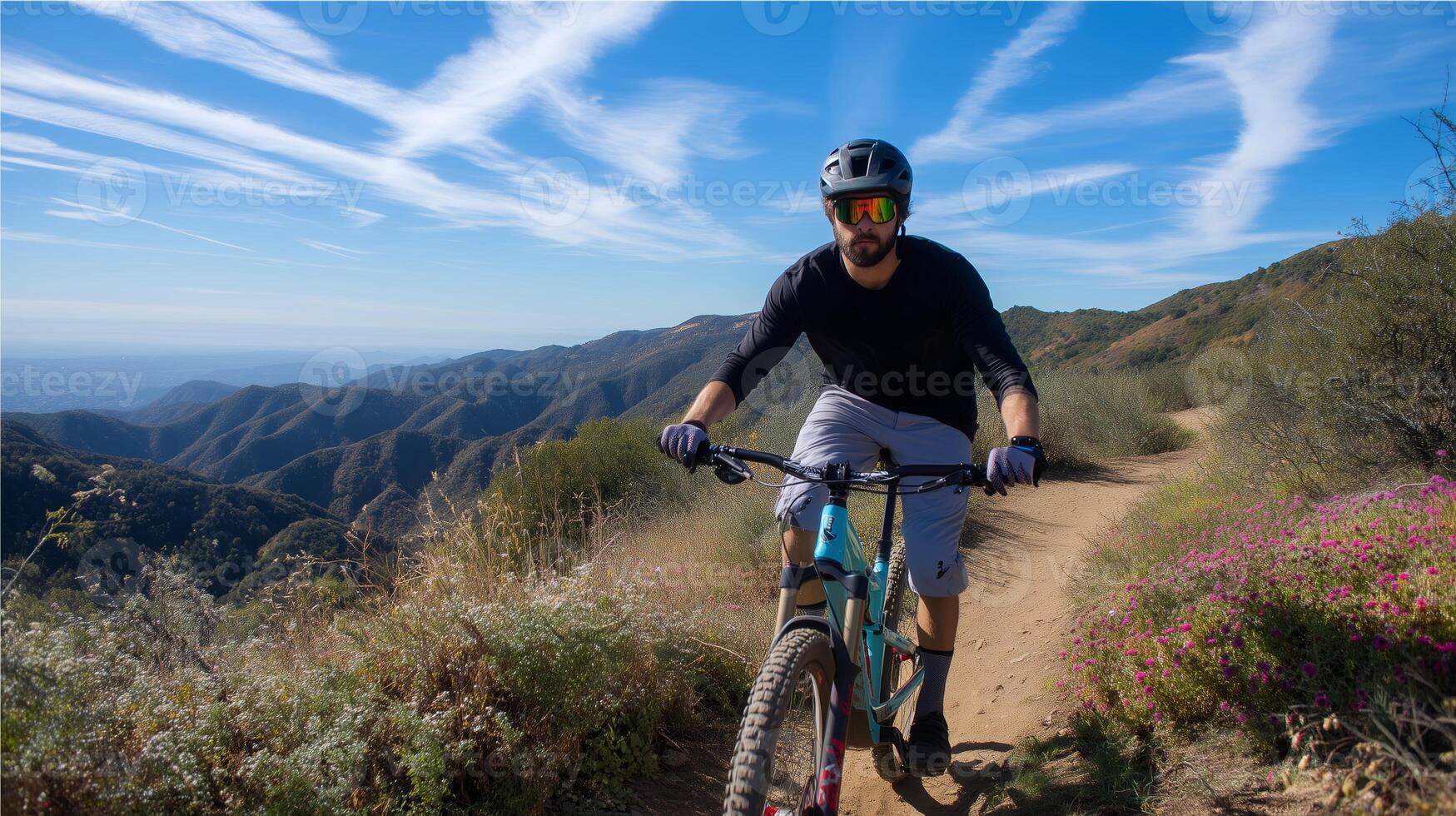 Mountain biker navigating a scenic trail in a sunny landscape with blue skies and distant hills photo