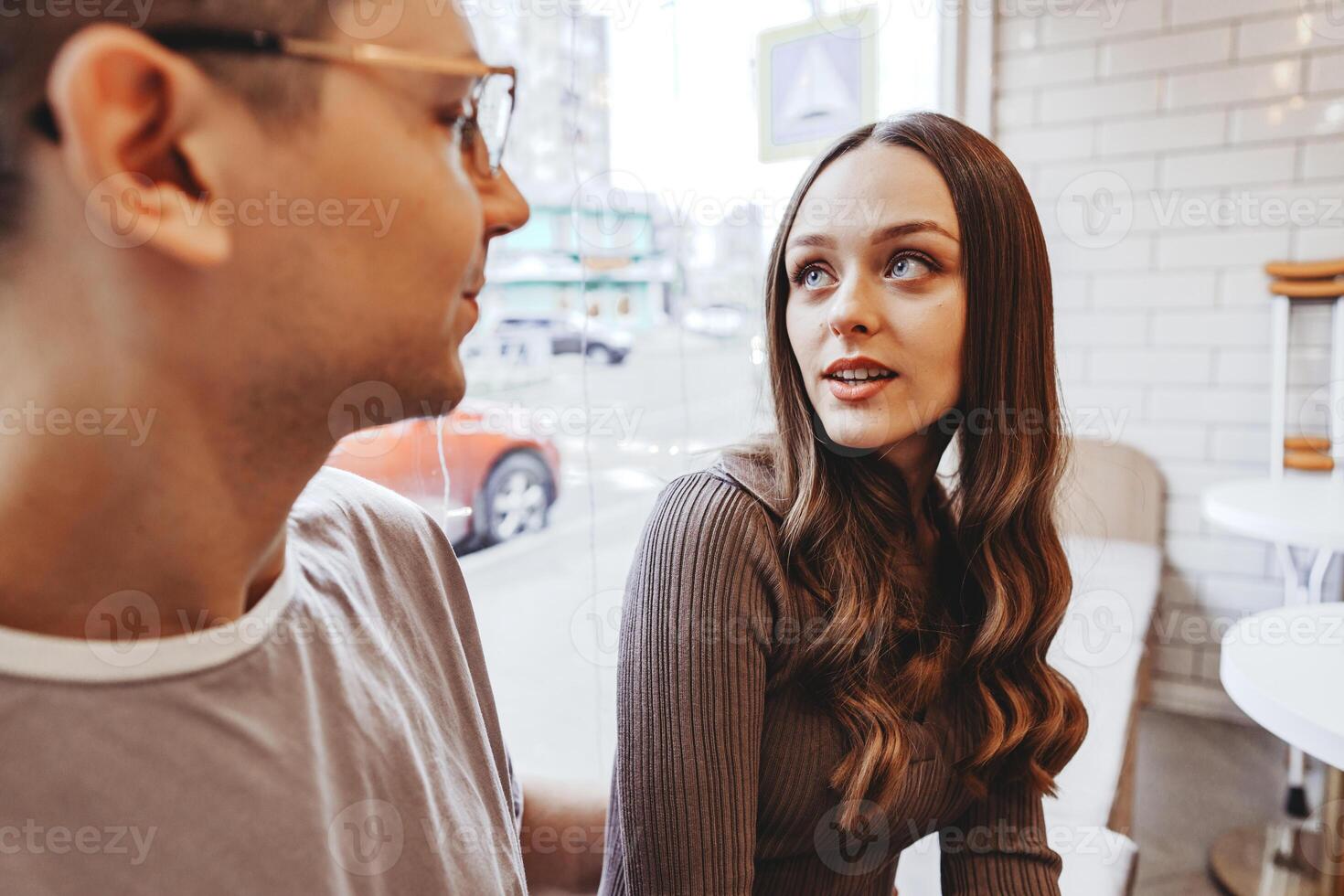 Engaging conversation between two young adults in a cafe during a sunny afternoon in a city photo
