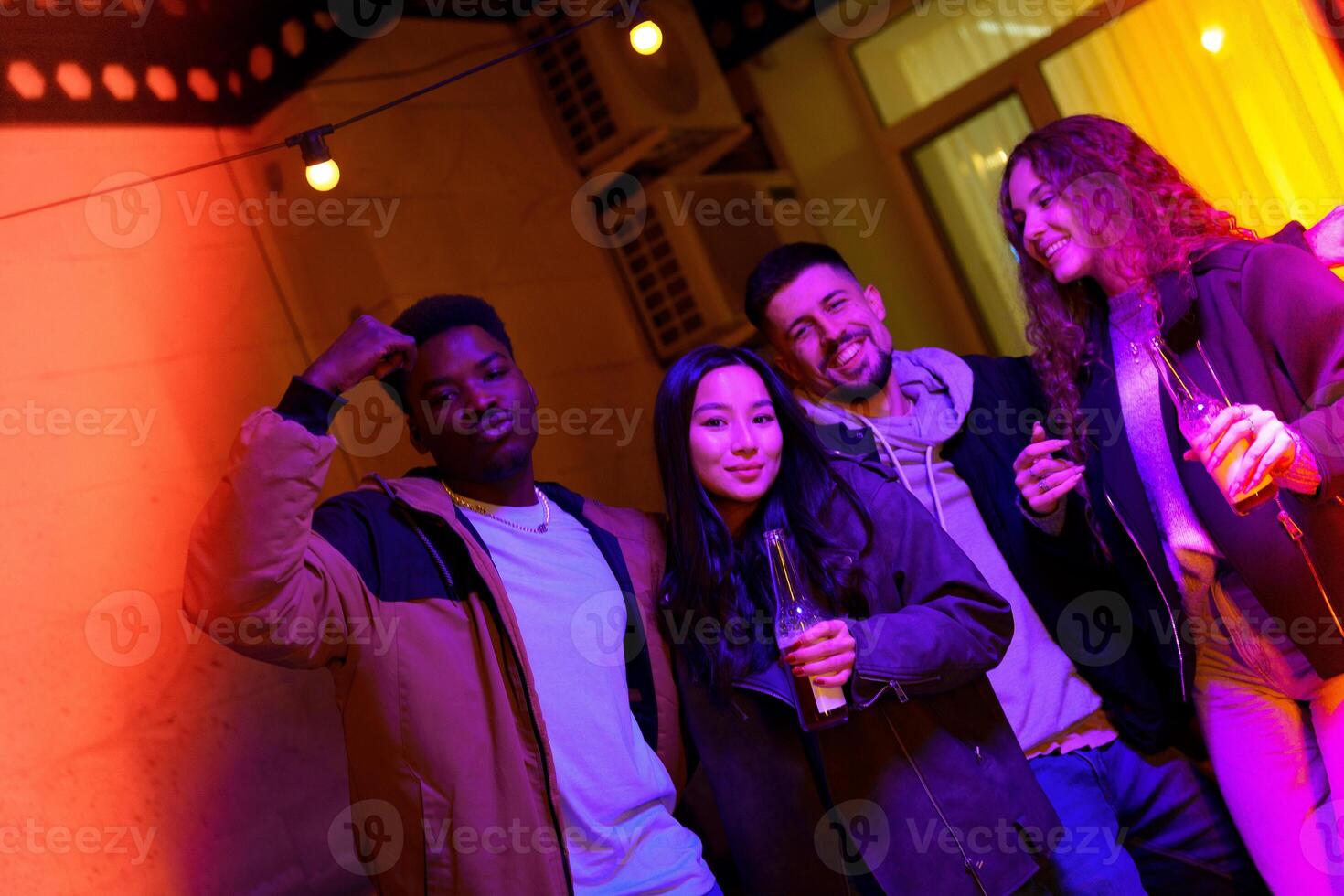 Friends enjoying a lively evening at a cozy indoor gathering with colorful lighting and drinks photo
