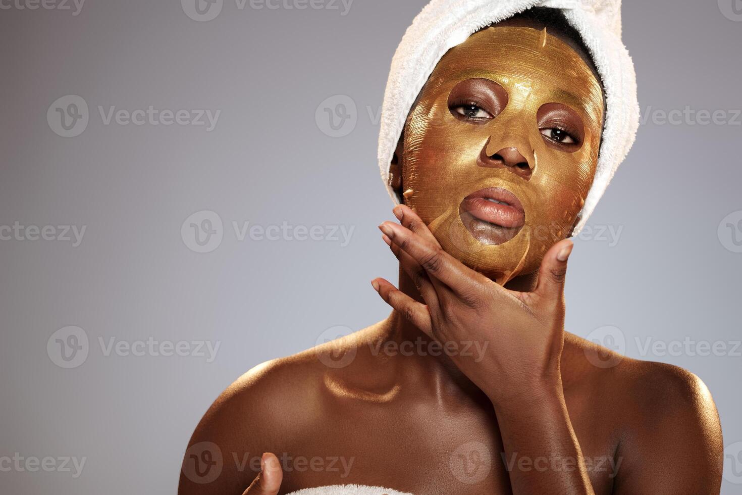 Woman applying gold facial mask during skincare routine at home in the evening photo