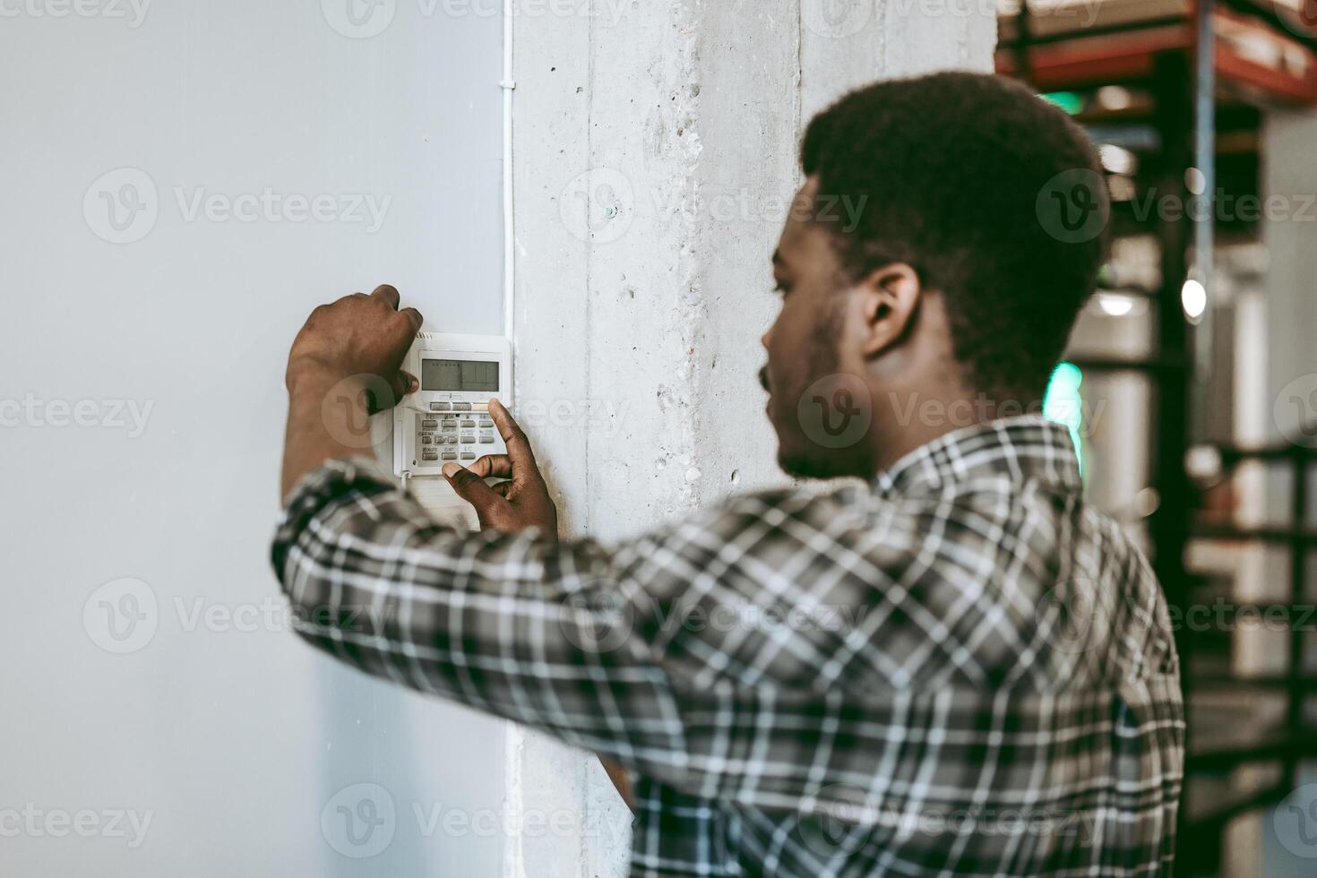 Individual configuring a security system in an industrial workspace during daylight hours photo