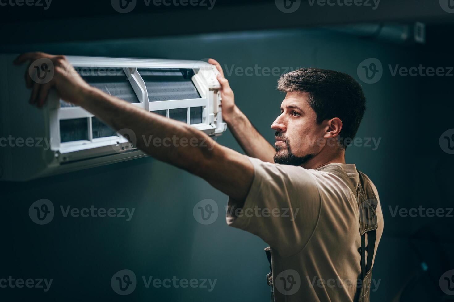 Technician installs a new air conditioning unit in a residential space during a warm afternoon photo