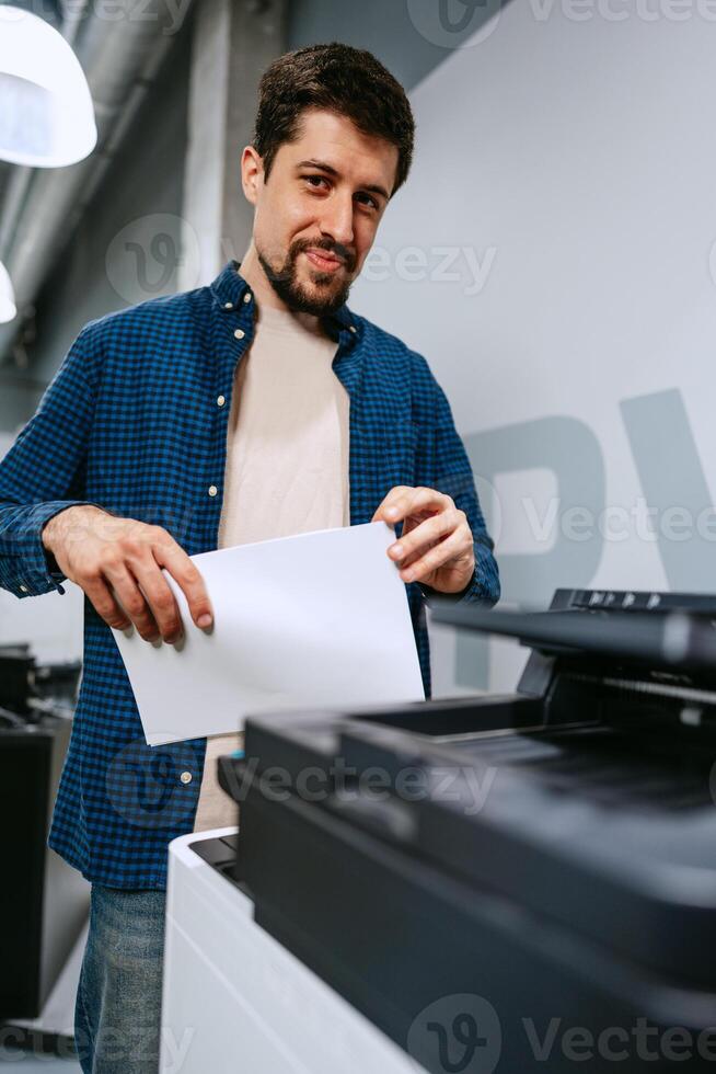 Man operates printer in modern office space while preparing printed documents for work tasks photo