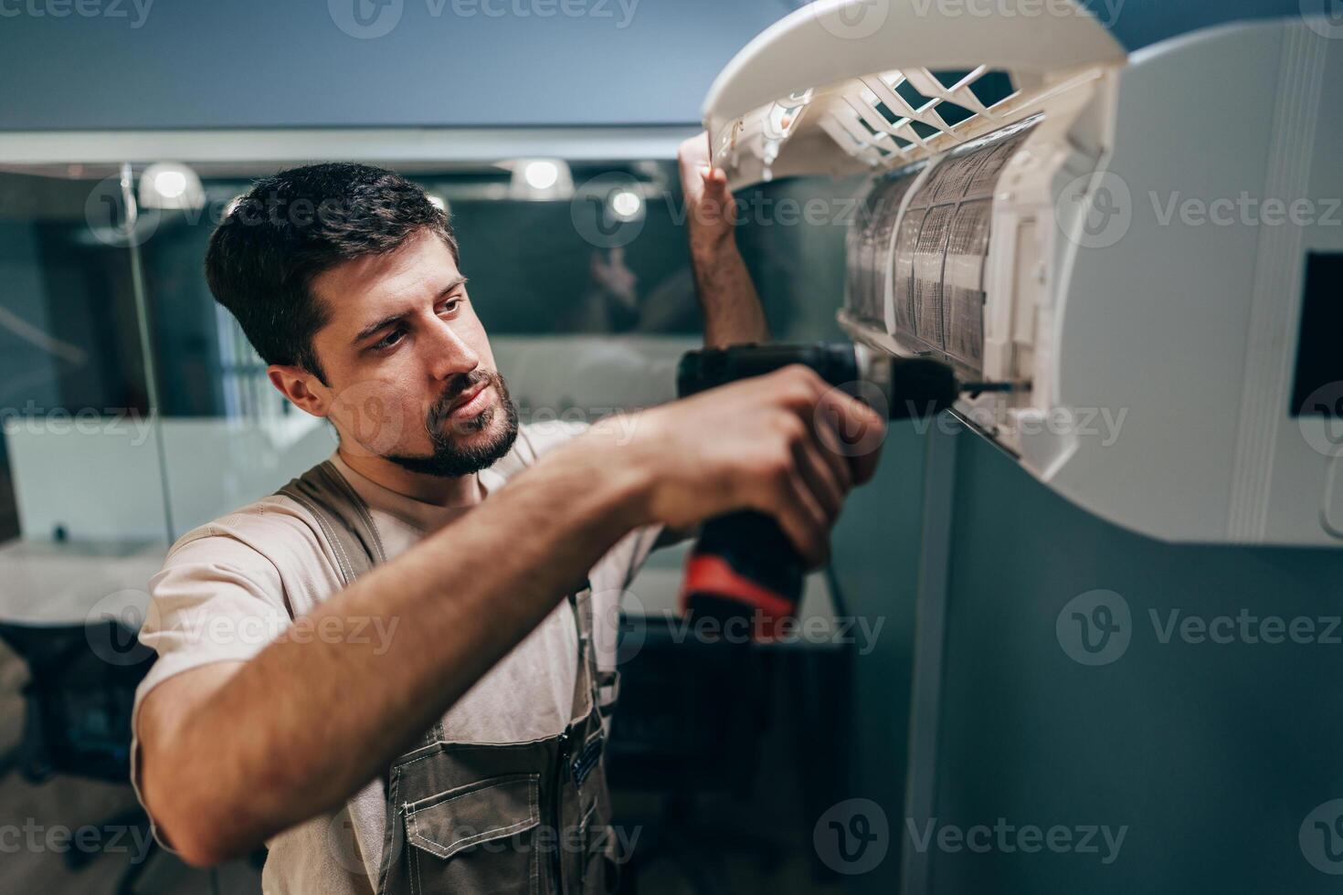 Technician installs air conditioning unit indoors in a modern office setting during the day photo