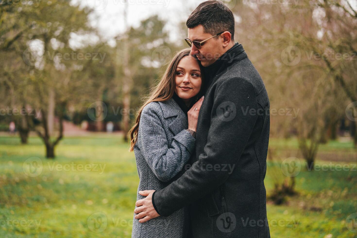 Couple enjoys intimate moment together in a serene park during a cool afternoon photo