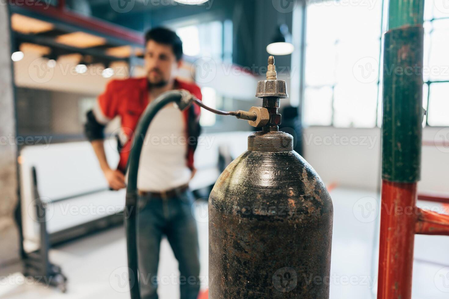 Worker inspecting a gas cylinder in a modern workspace during daylight hours photo