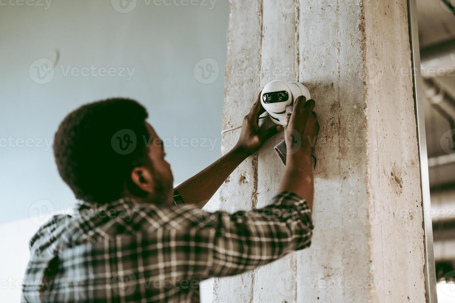Technician installing security camera in modern office space during daylight hours photo
