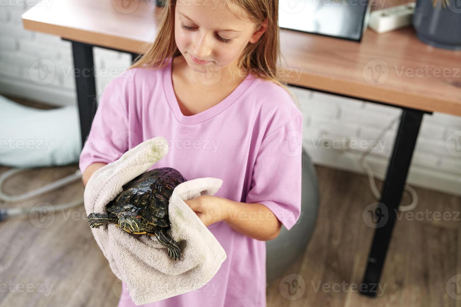 Young girl carefully holds a turtle wrapped in a towel in a cozy indoor space during the day photo
