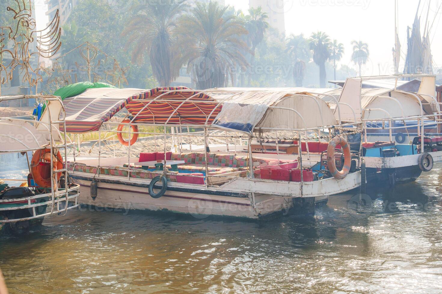 Colorful boats resting on a tranquil river under palm trees in a sunny afternoon photo