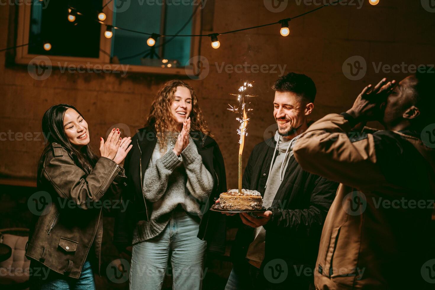 Celebration with friends and a sparkling cake during nighttime gathering in cozy atmosphere photo