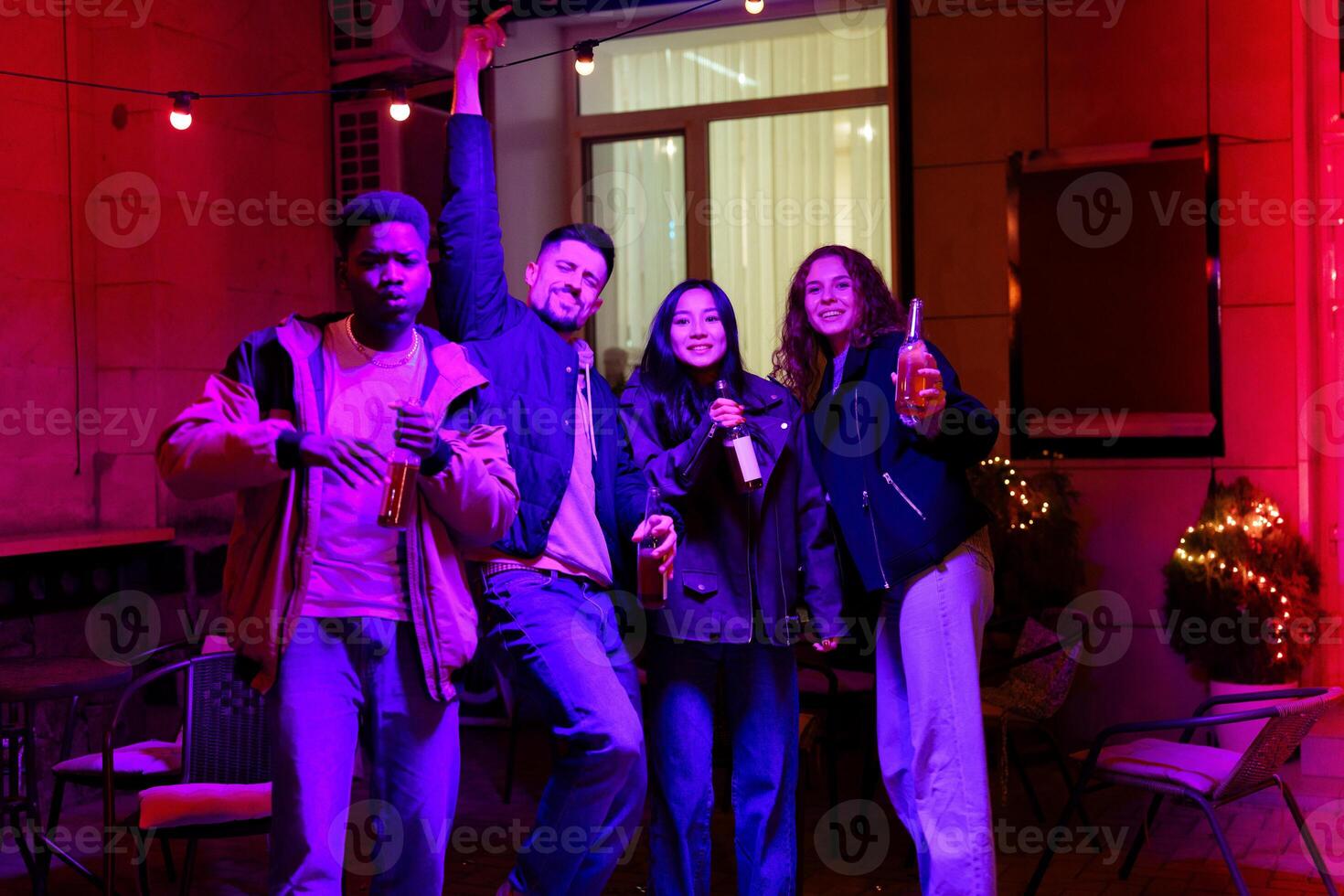 Group of friends celebrating at a vibrant evening gathering with drinks in hand photo